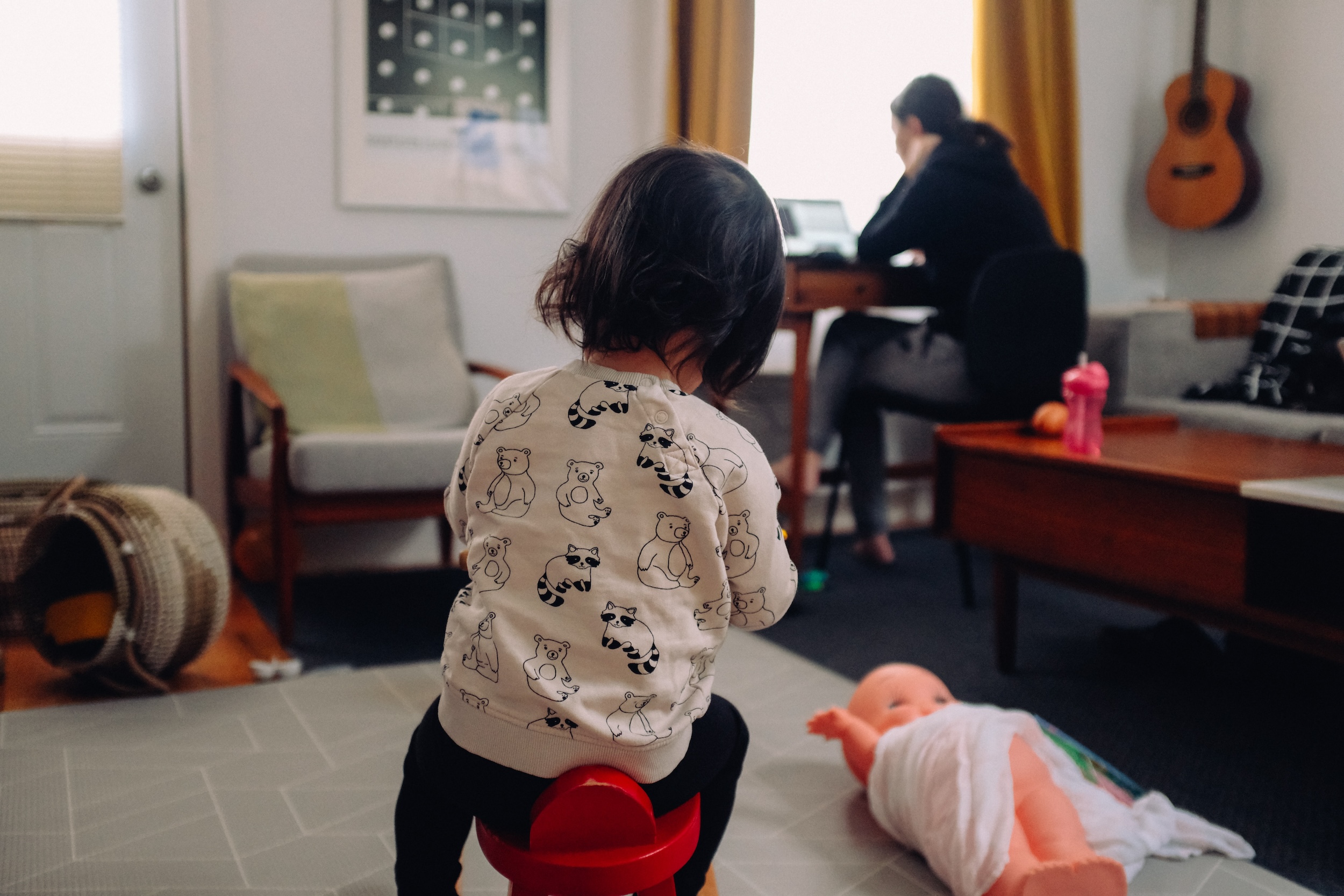 baby plays at home while mom is working on laptop
