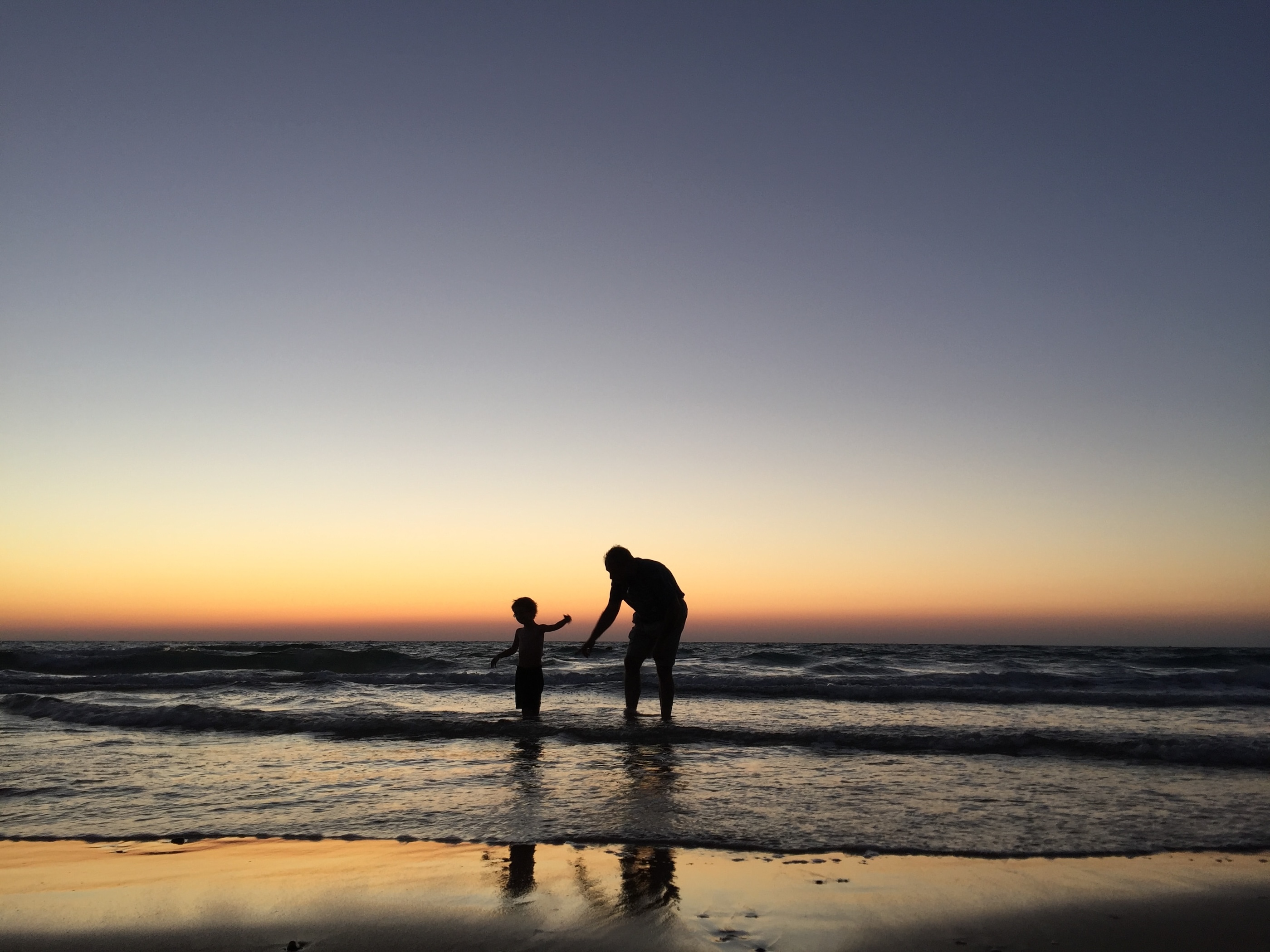 father and child on the beach at sunset